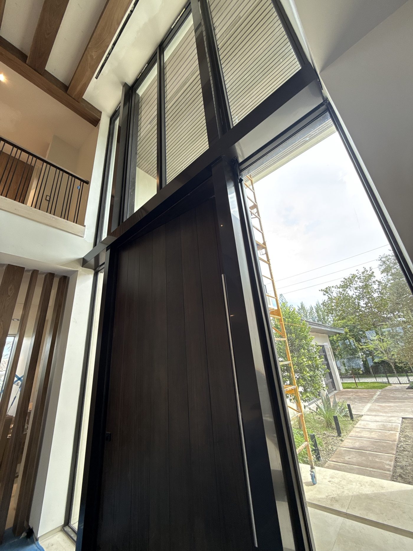 Custom break metal wrapping a double-height entry glazing system and pivot door
