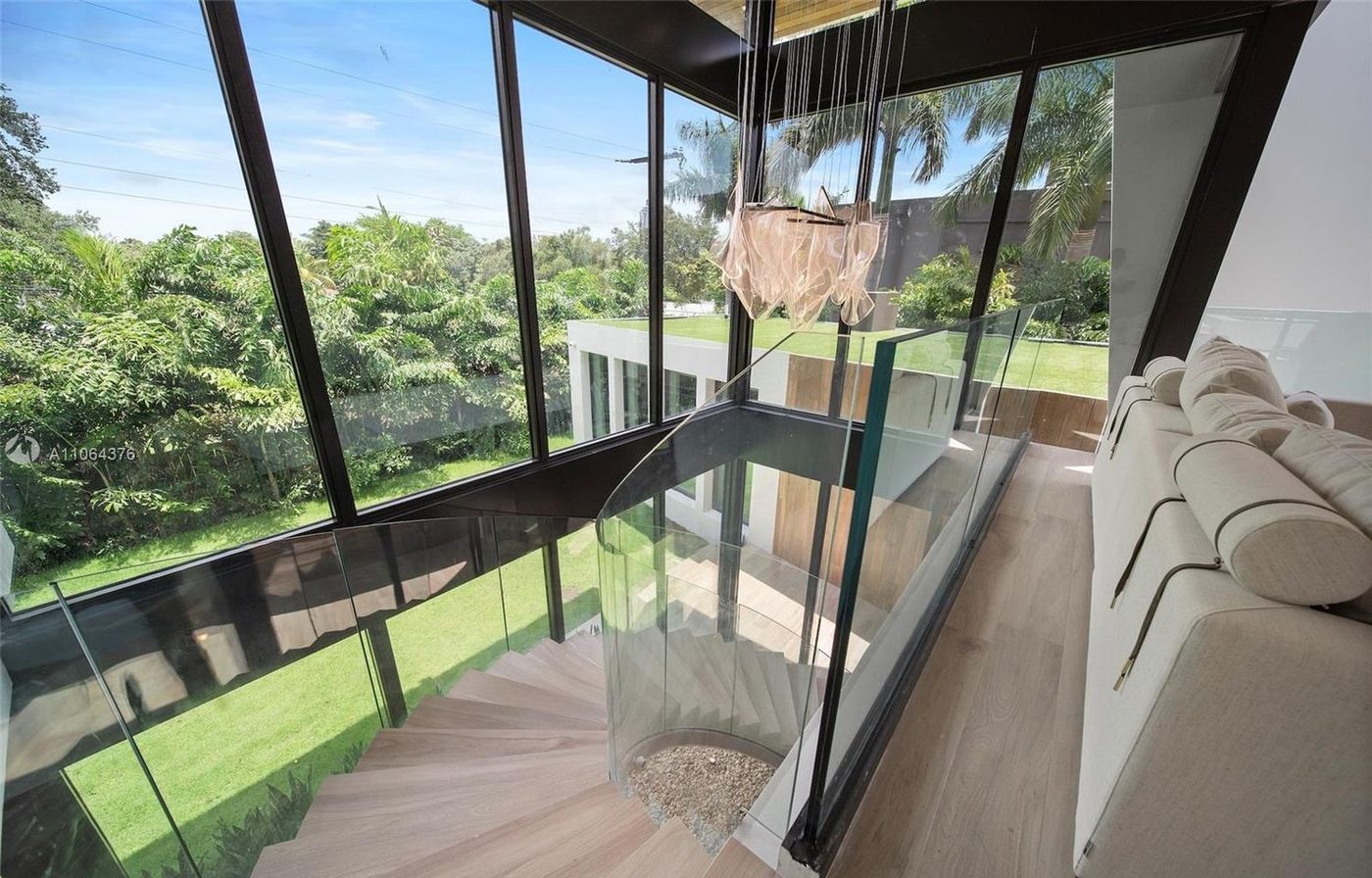 Glass-railed bridge crossing the double-height void with floor-to-ceiling glass beyond