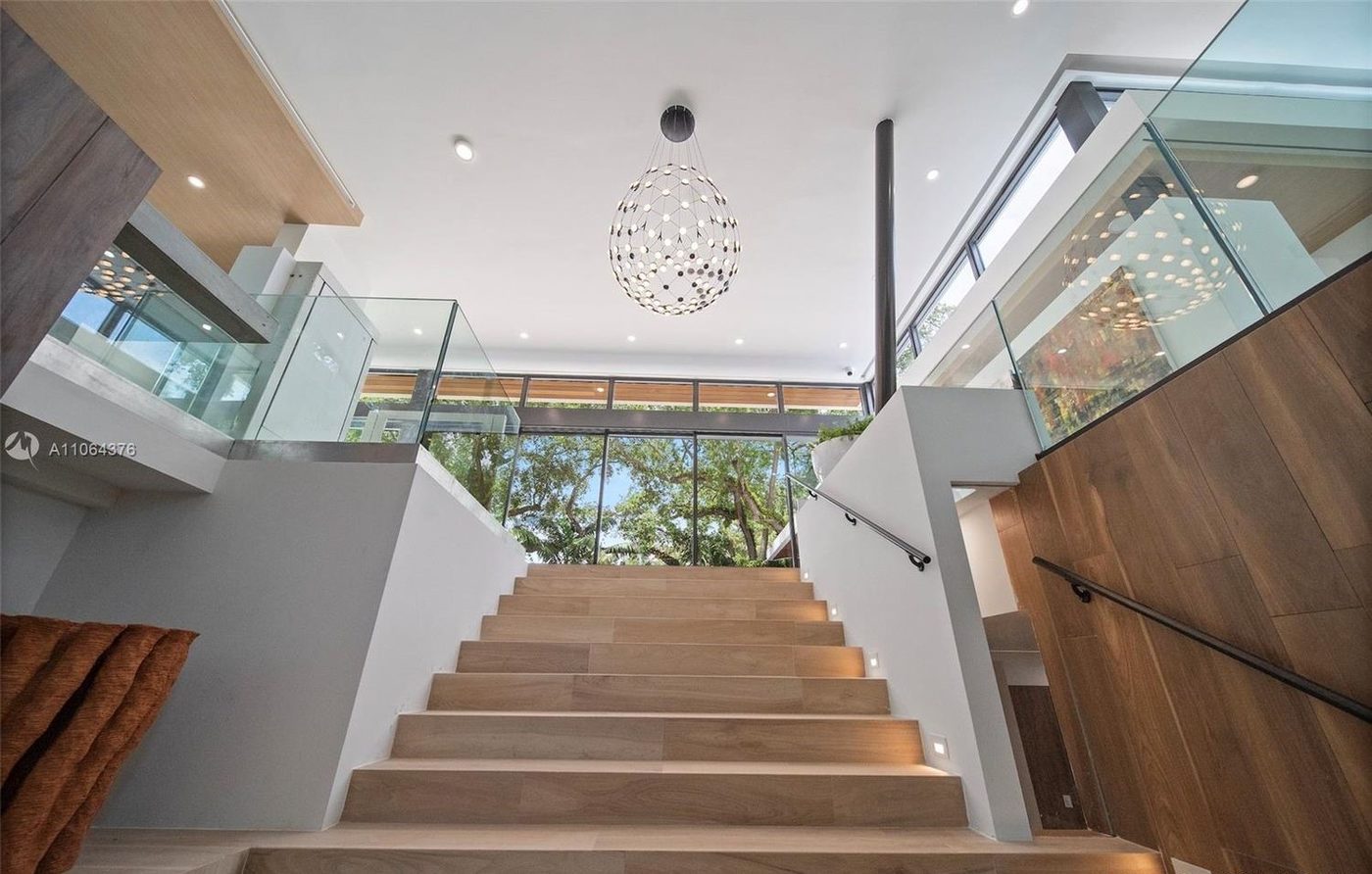 Main stair rising to the upper level between frameless glass railings