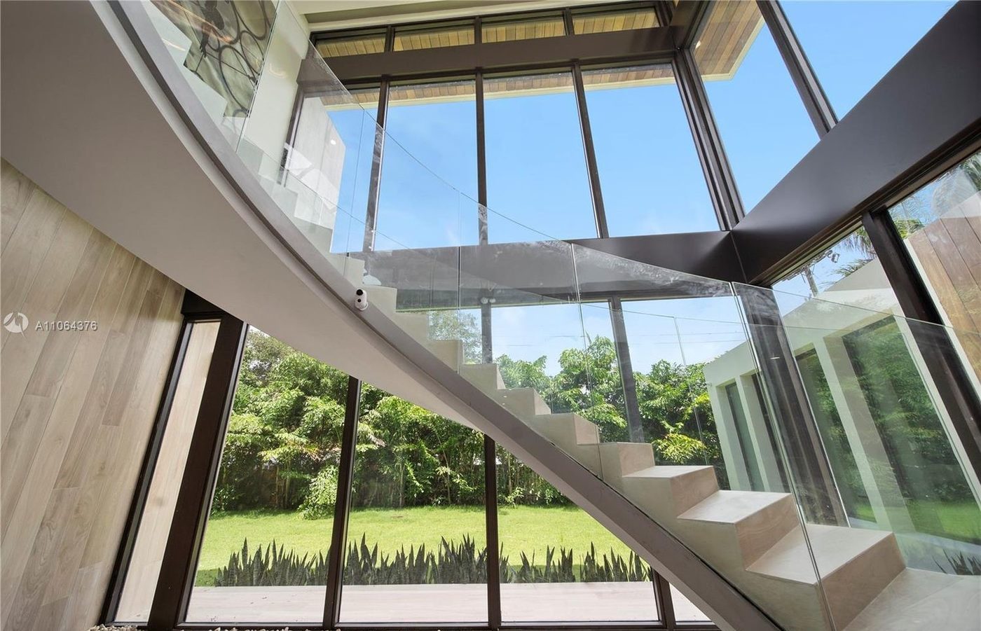 Curving stair with glass railing against a full-height glass wall