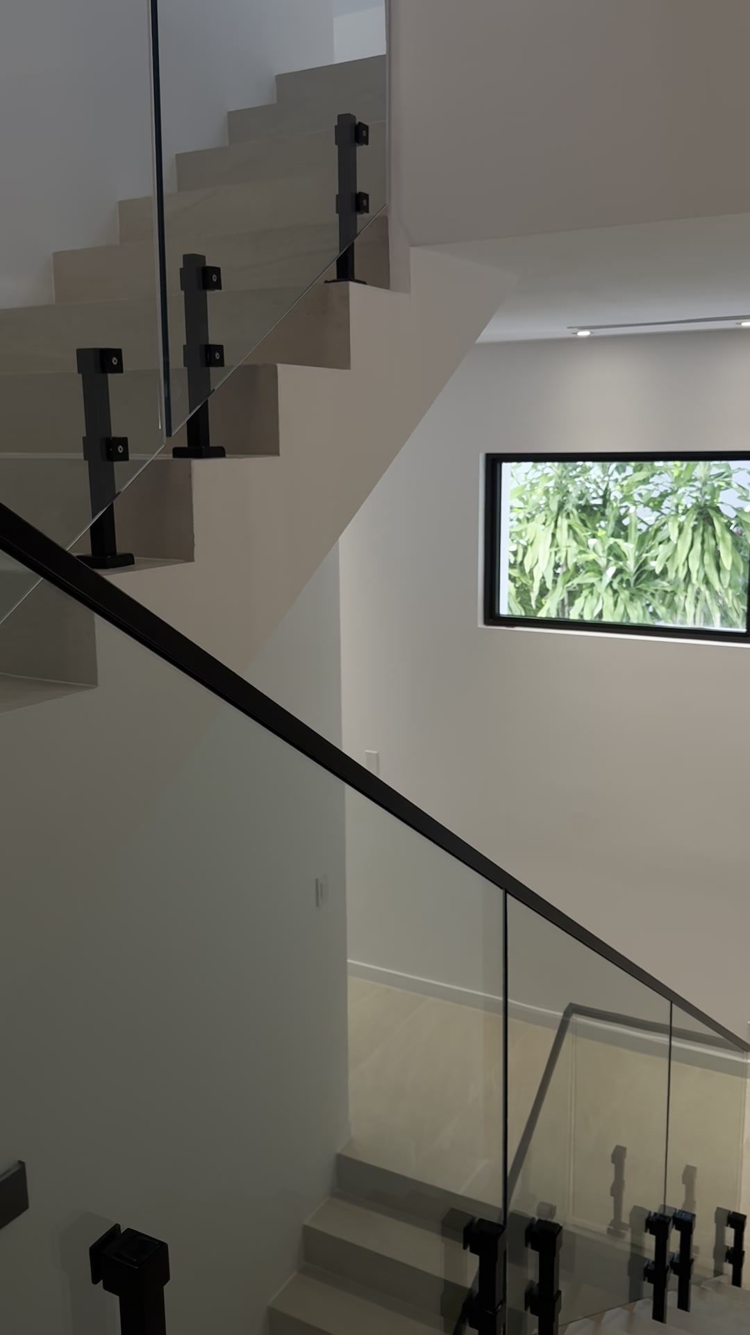Glass railing and black cap rail following the stair between levels