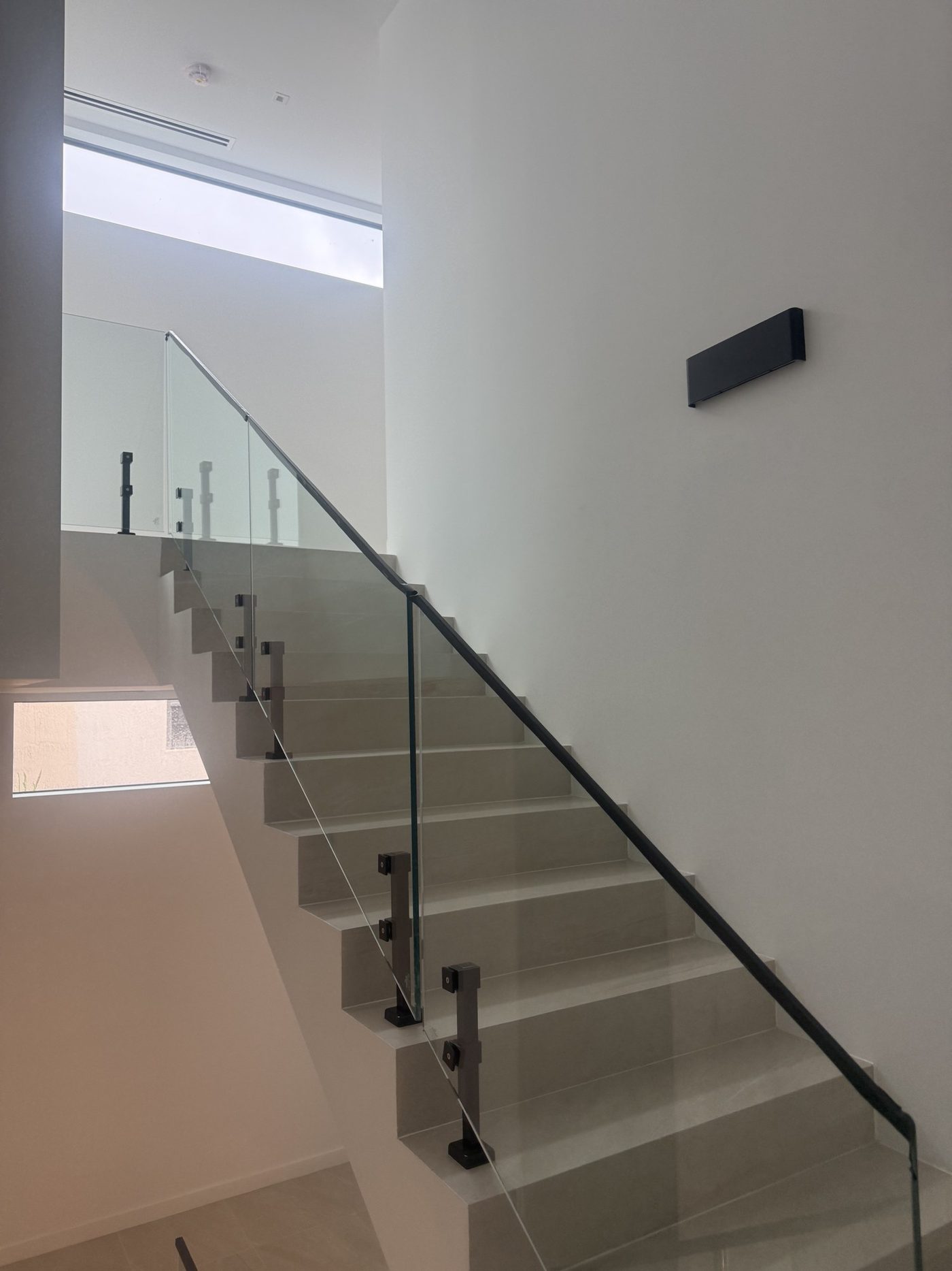 Frameless glass stair railing on black posts in a Coconut Grove townhome