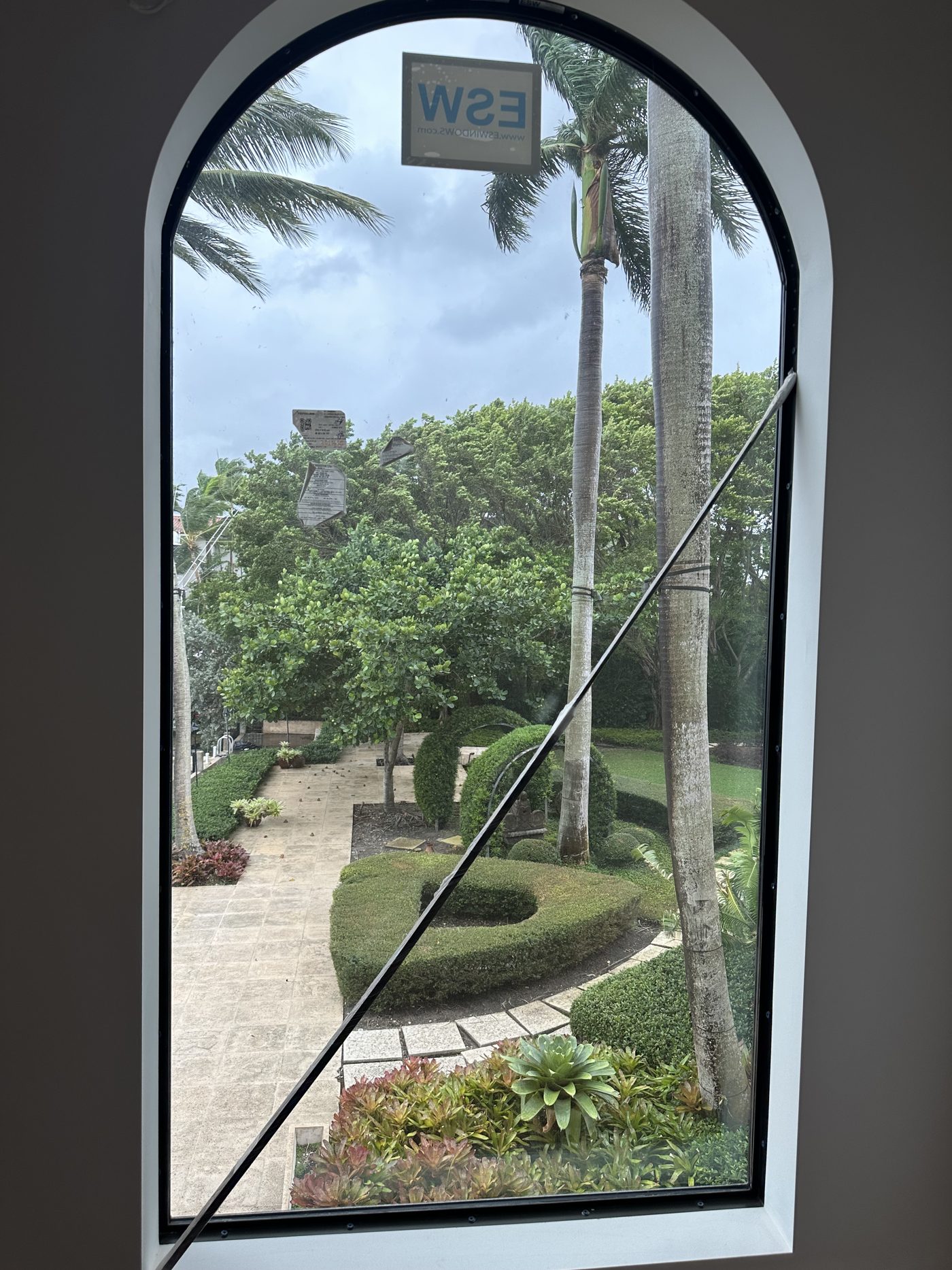 Arched ESW impact window framing the formal garden