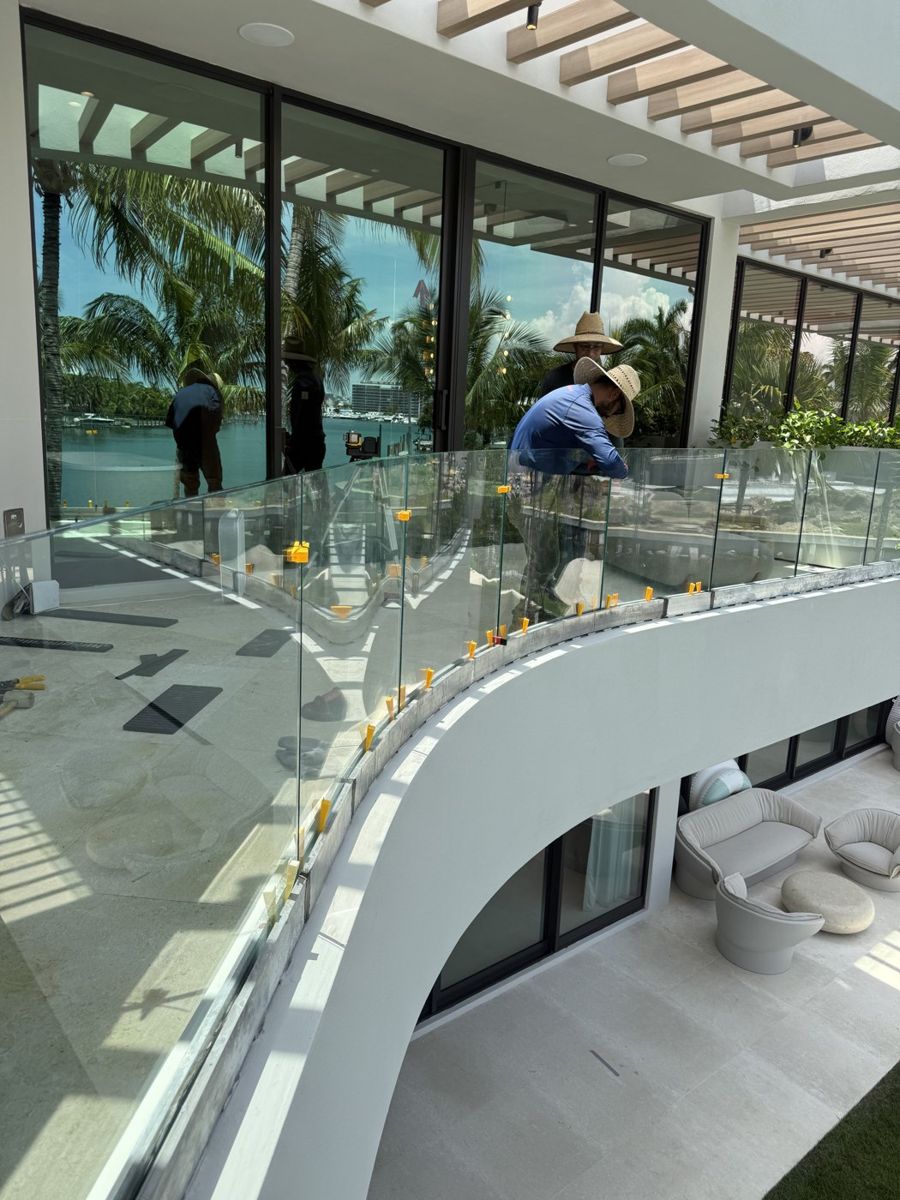 Crew setting curved frameless railing over the pool