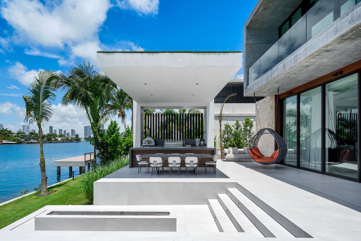 Covered terrace with sliding glass walls and glass railing facing the bay