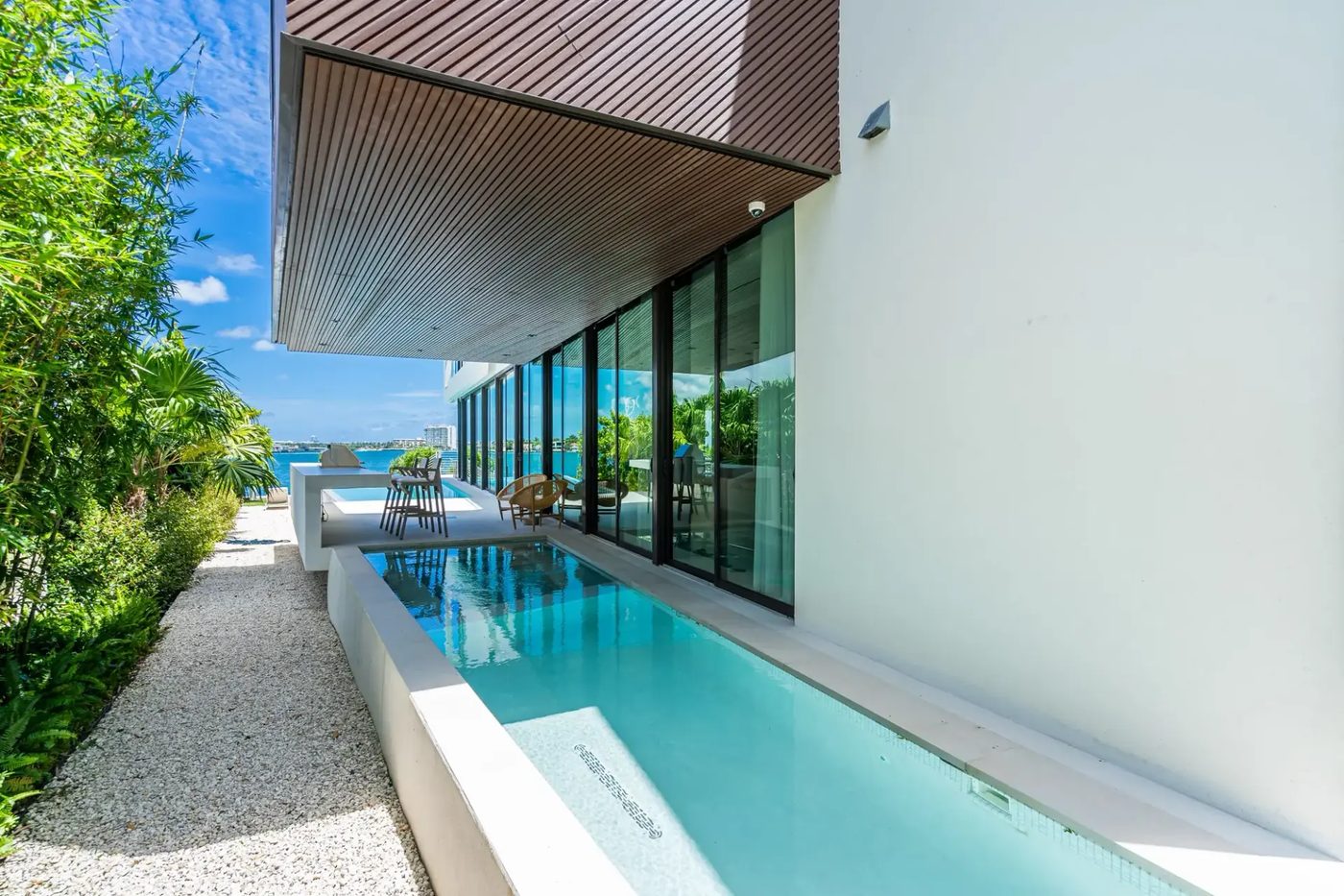 Floor-to-ceiling sliding glass along the lap pool, looking out to the bay