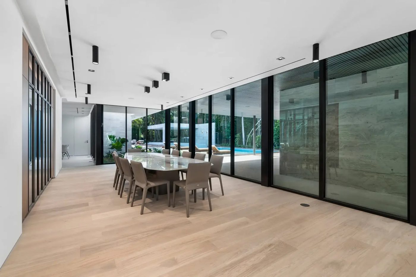 Dining room lined with full-height glass looking out to the pool