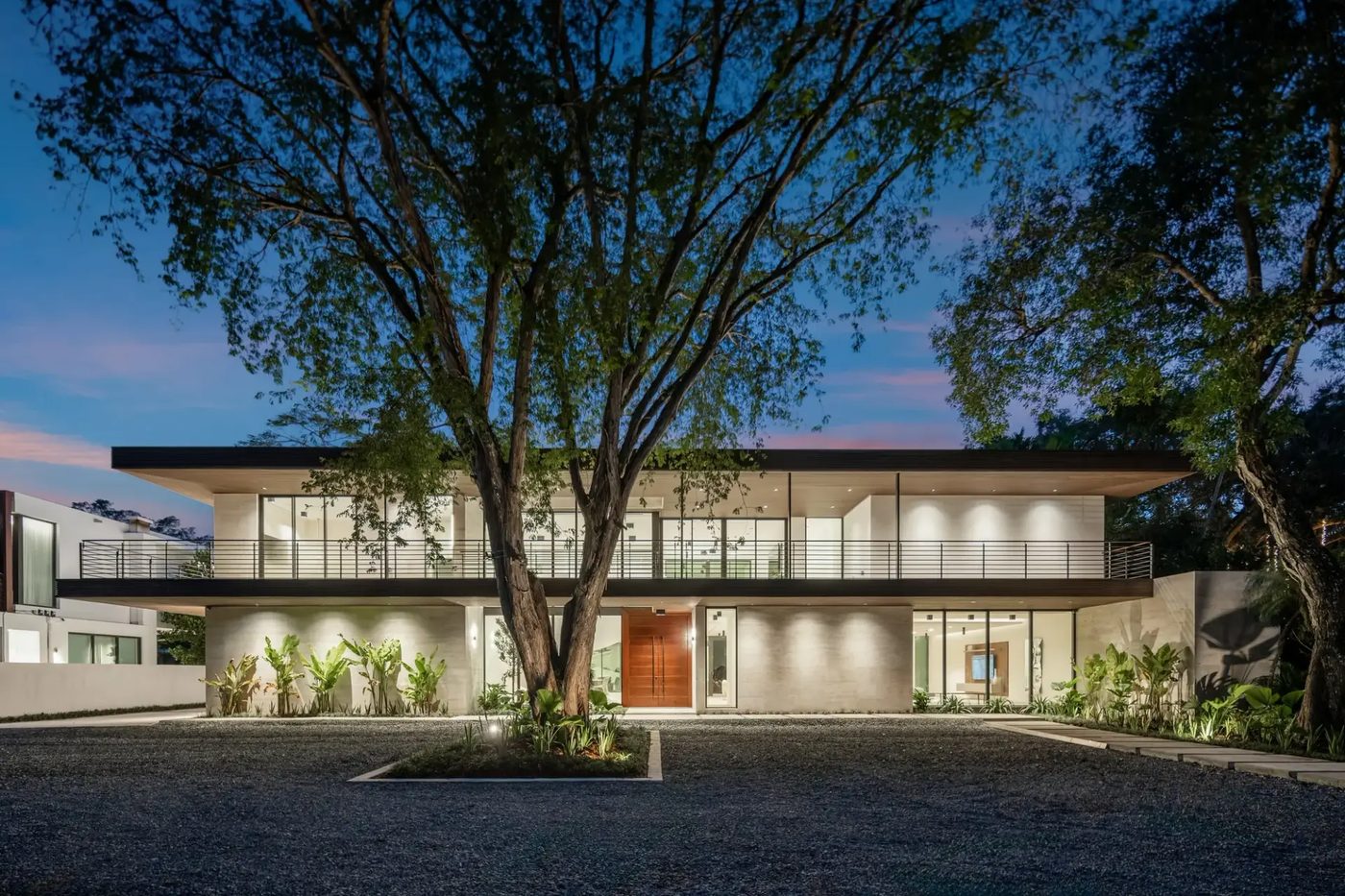 Front facade of the Kiaora Residence at dusk behind a mature shade tree