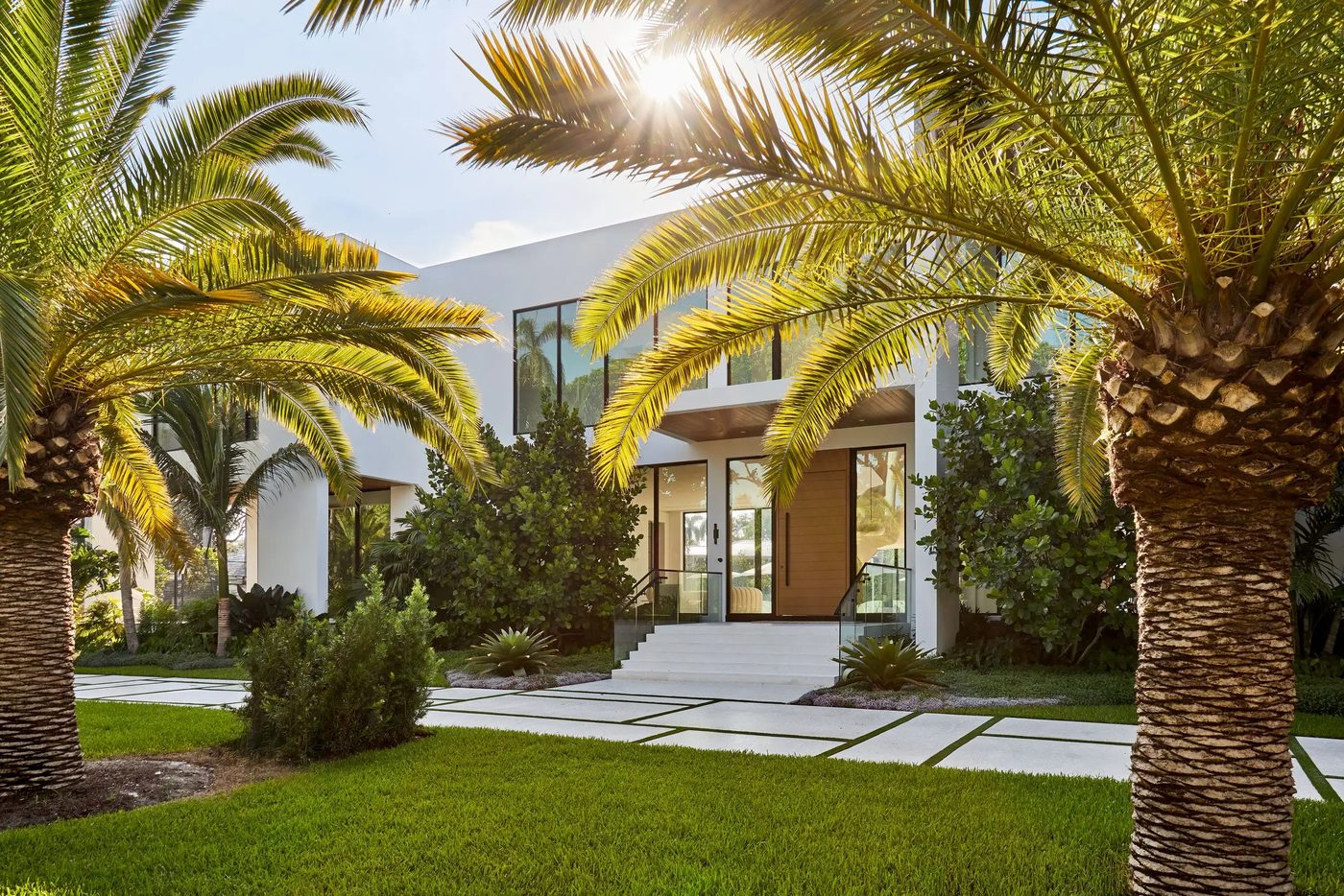 Front entry with frameless glass stair railings framed by palms