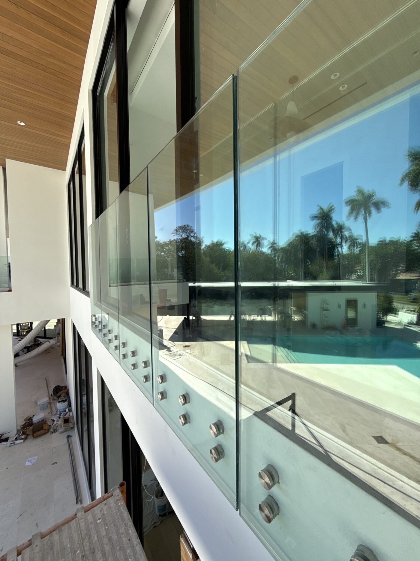 Standoff-mounted balcony glass going in above the pool, before final cleaning