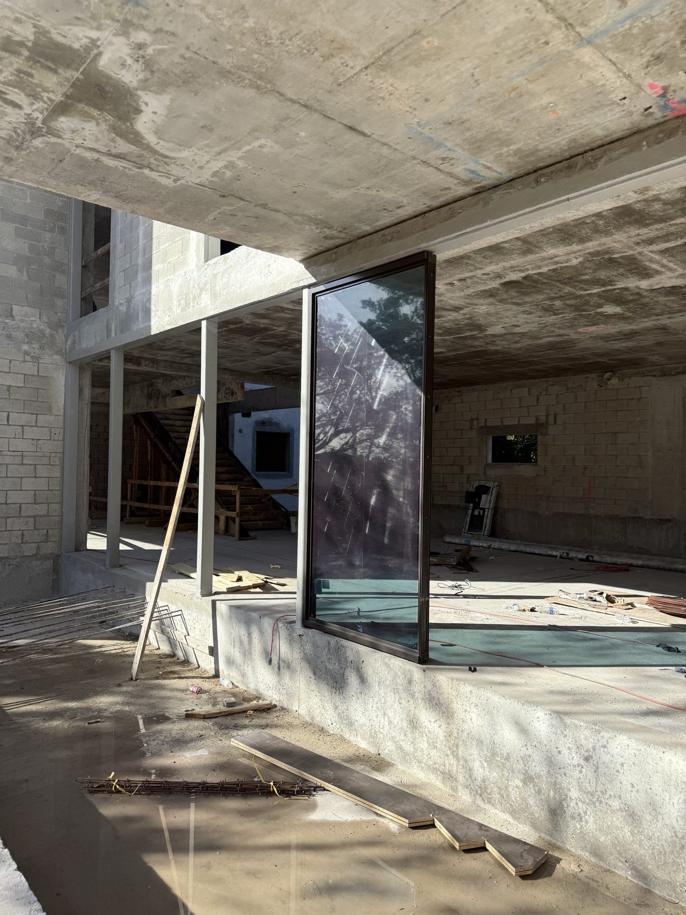 An oversized glass unit set into the raw concrete shell of a custom home in Manalapan