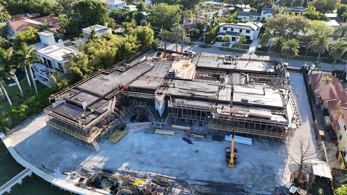 Aerial of a waterfront custom home under construction in Miami Beach, concrete frame going up on the bay