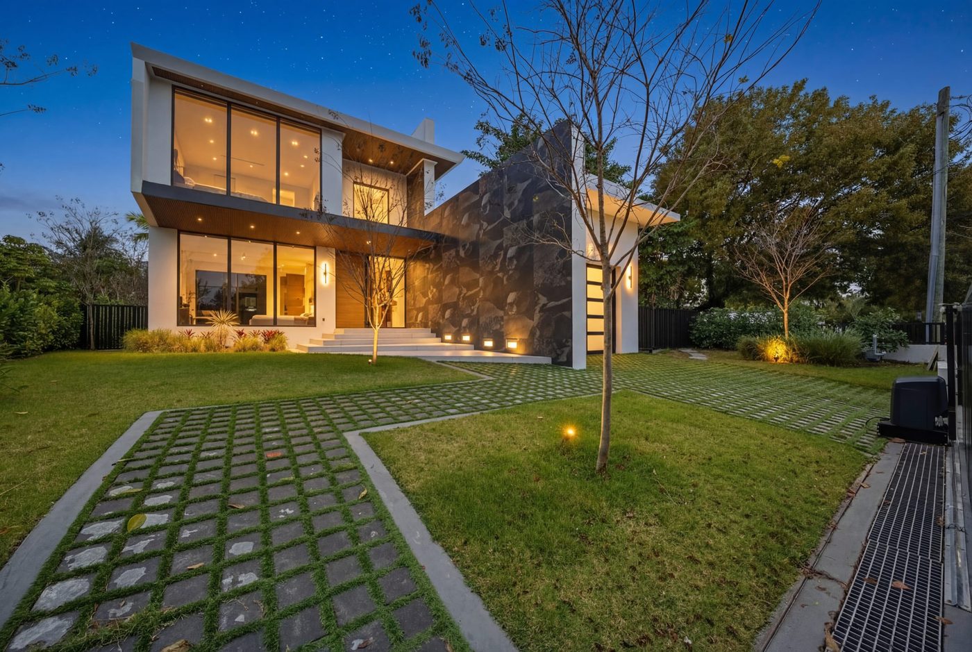 Normandy Shores spec home at dusk, its glass walls lit from within