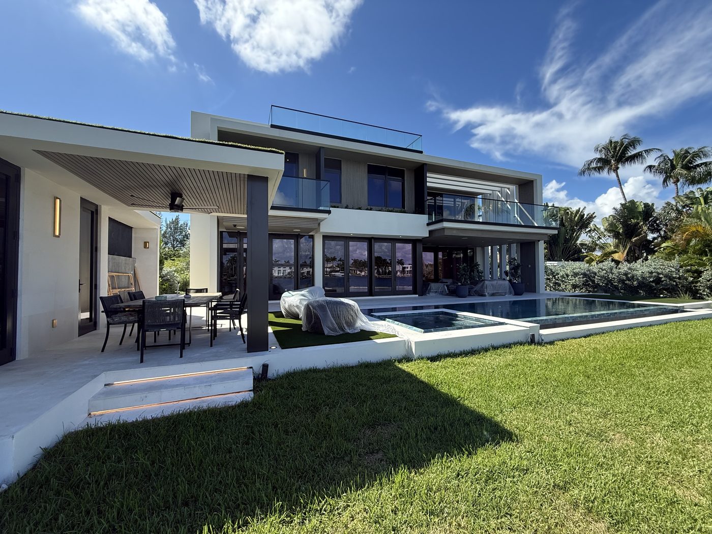 Loggia and pool with folding doors below and frameless glass balcony railings above