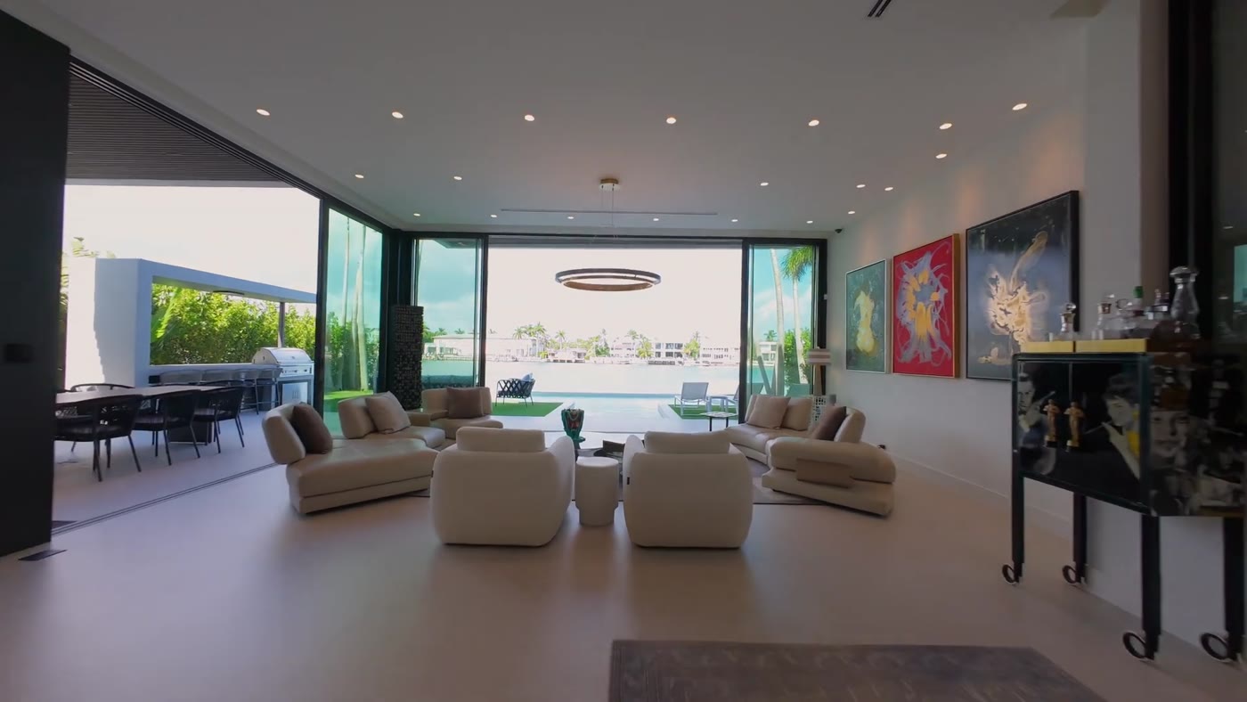 Living room with floor-to-ceiling sliding glass opening to the pool and bay