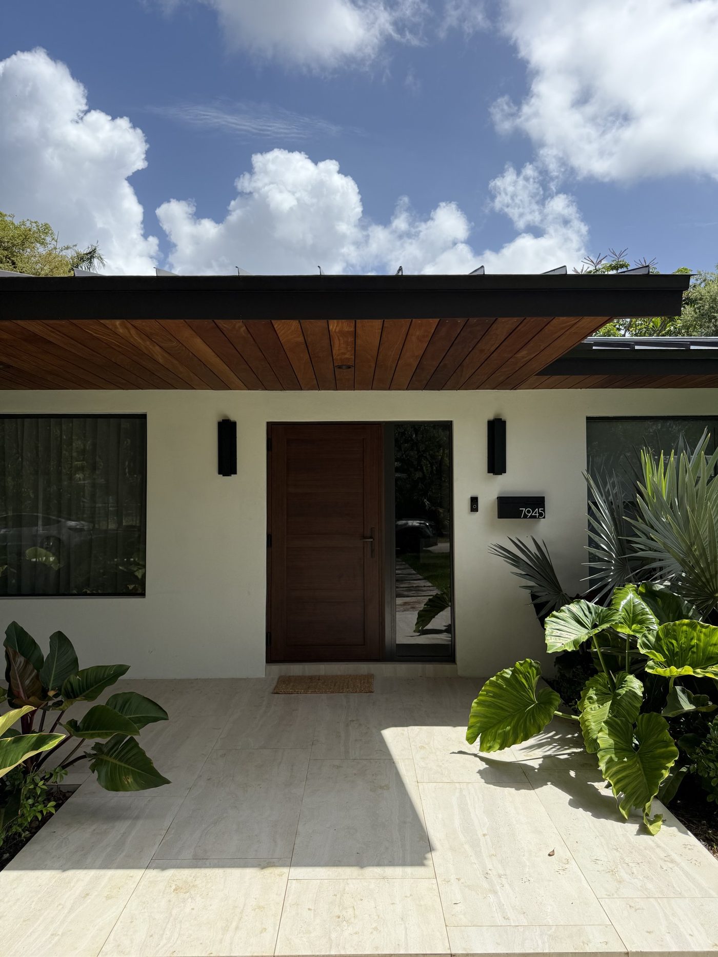 Wood-grain impact entrance door under a cedar soffit