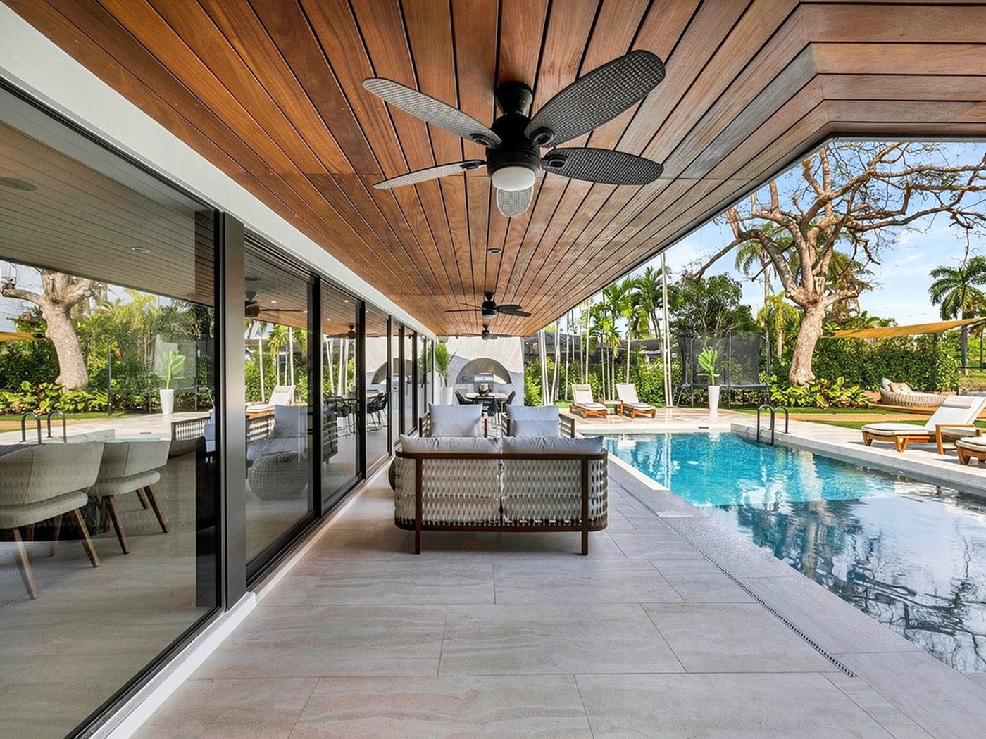 Covered loggia lined with floor-to-ceiling impact sliders beside the pool
