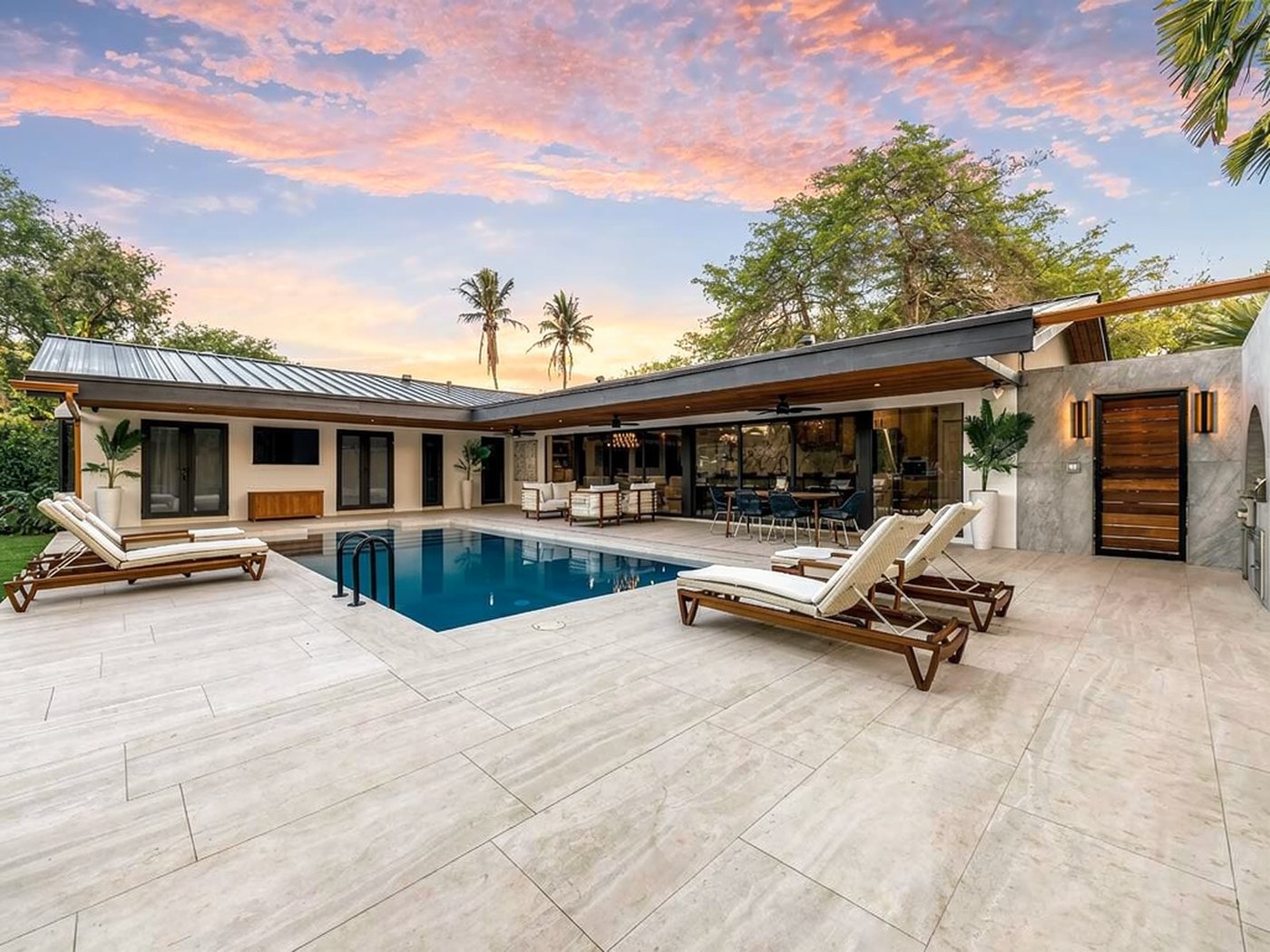 Pool terrace at sunset, with impact sliders and French doors lining the L-shaped rear of the house