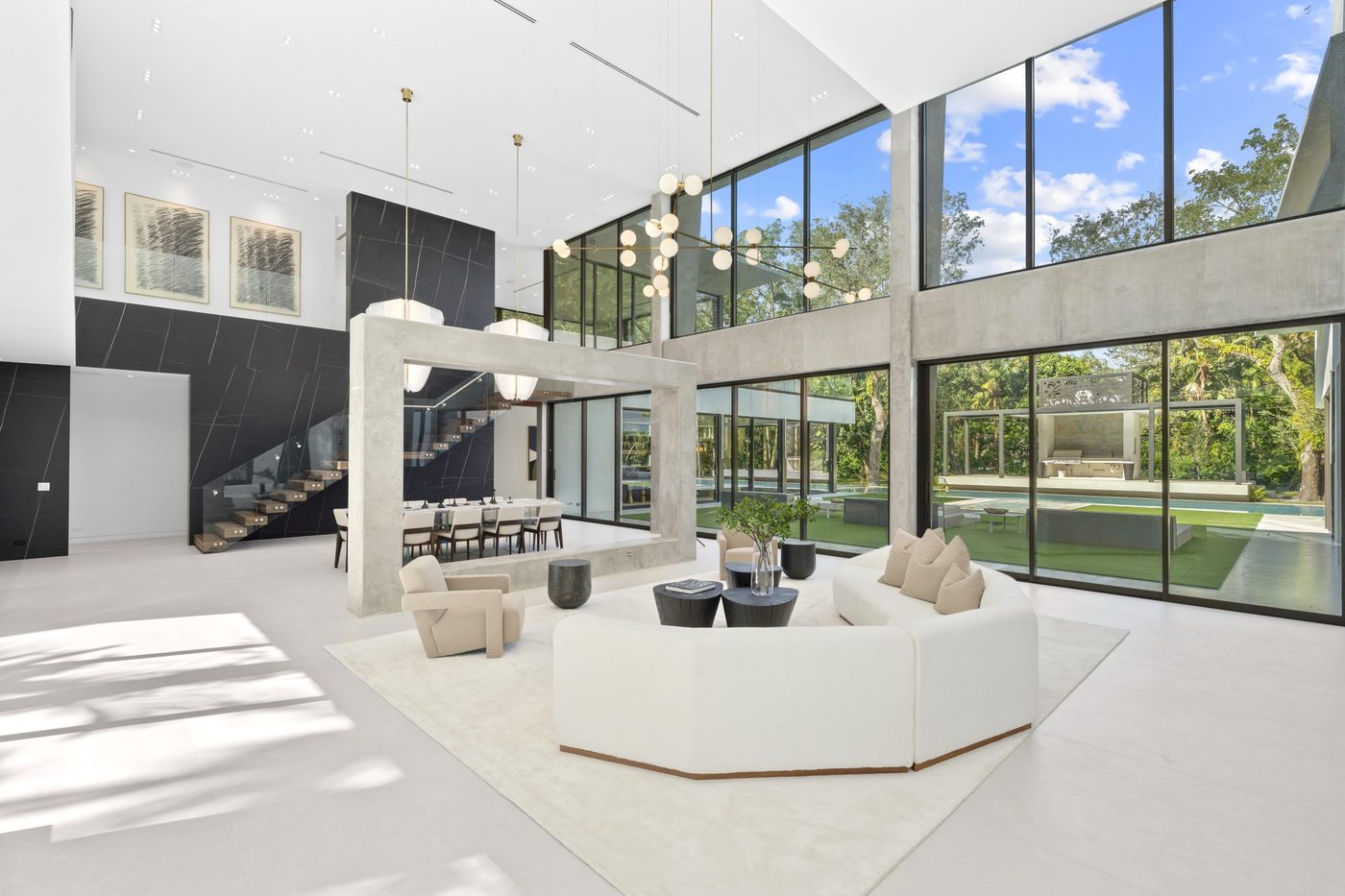 Double-height great room with two stacked tiers of glazing and sliding doors to the pool