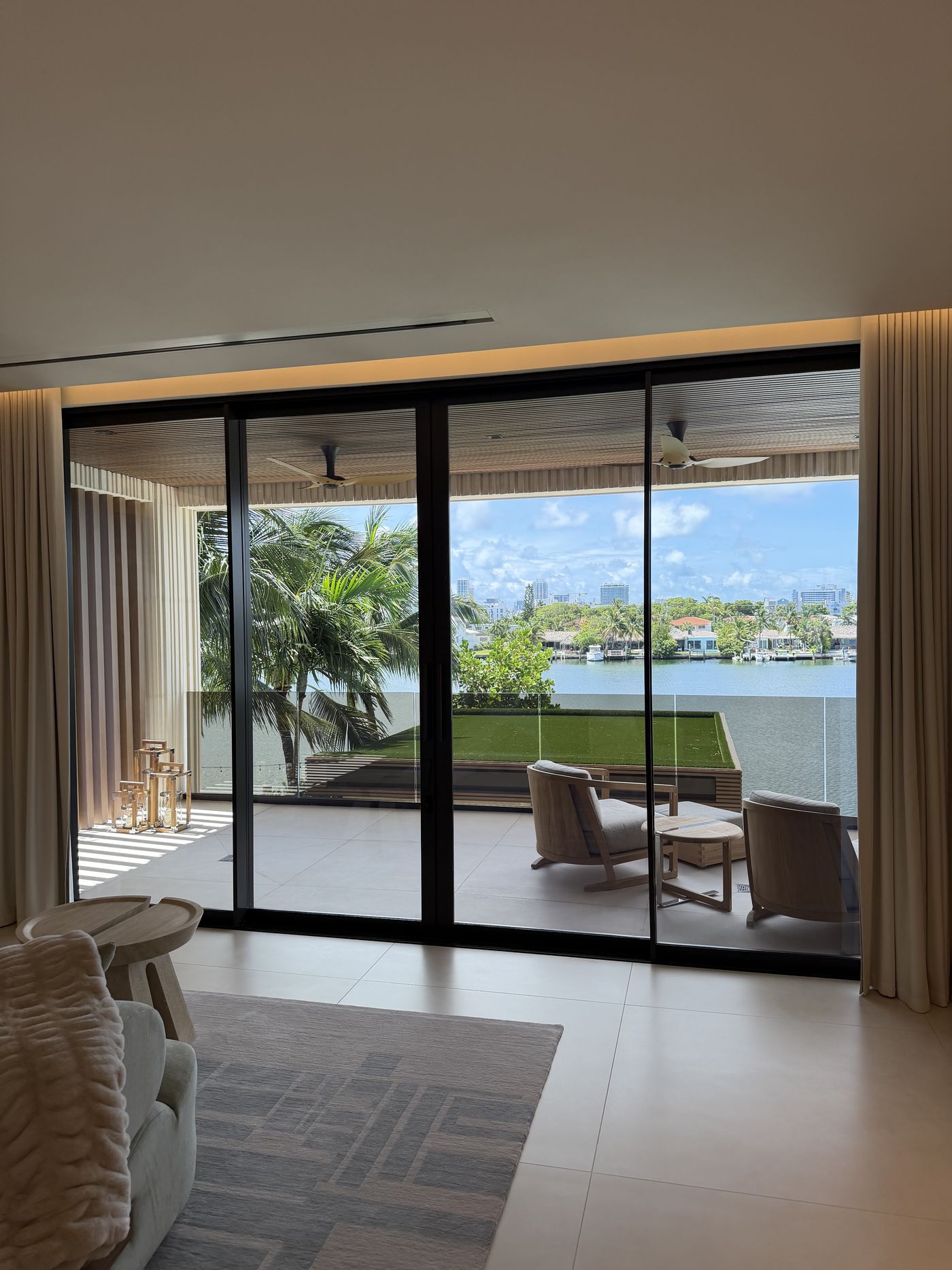 Eurowall flush-track sliding doors opening from a bedroom onto a waterfront terrace with glass railing