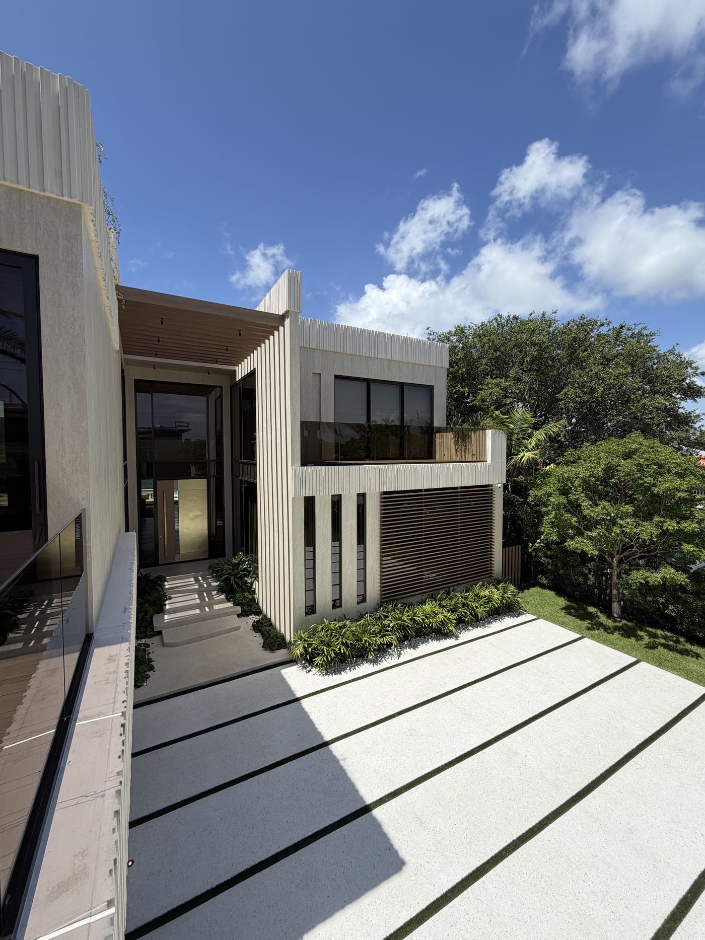 Front facade of the Surfside Residence with ESW curtain wall entry and glass balcony railing