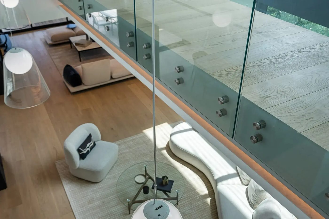 Standoff-mounted frameless glass railing along the mezzanine edge, seen from above