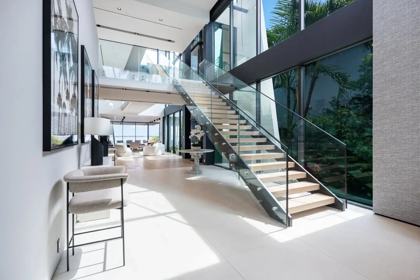 Open-riser staircase with standoff-mounted frameless glass railing in a double-height foyer